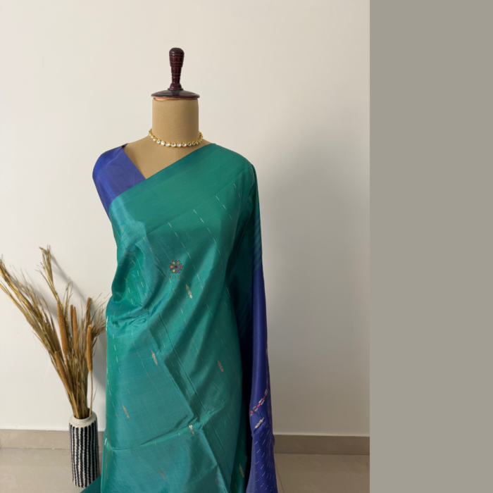 Teal and peacock green banana fibre saree with a rich royal blue pallu, featuring a textured finish and elegant contrast, suitable for festive and ethnic wear.